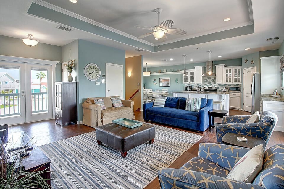 Relax in your spacious open-concept living area with coastal blues, comfortable seating, and modern kitchen access.