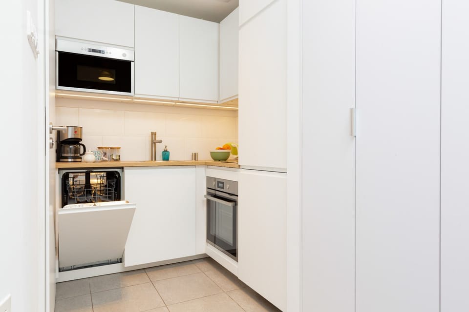 Modern and sleek kitchen with white cabinets and integrated appliances.