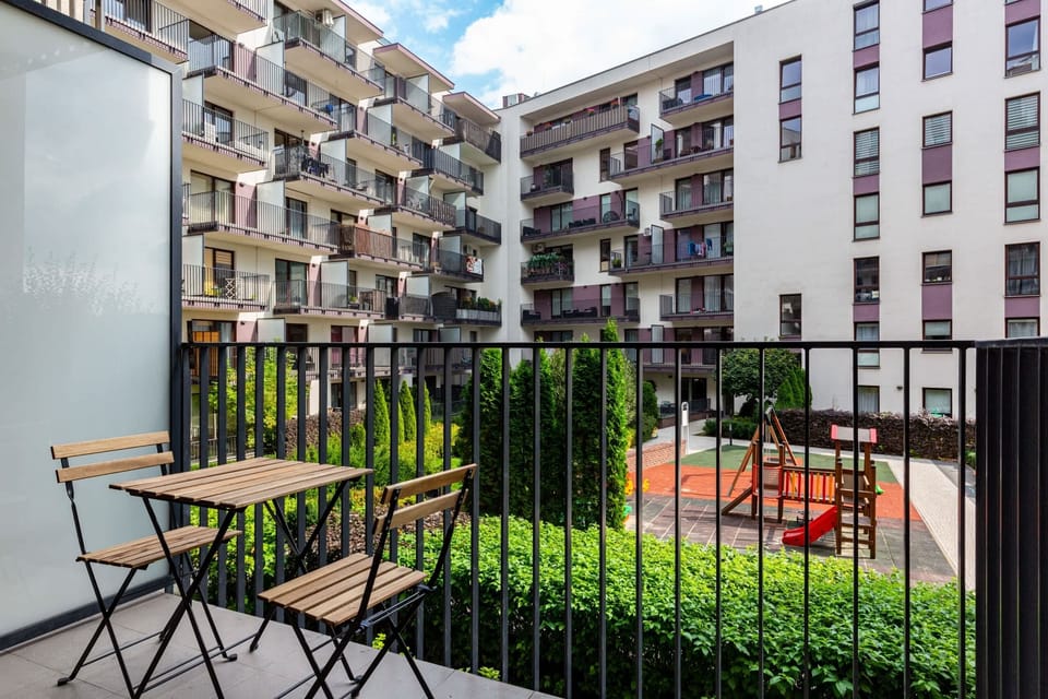 Private balcony with a seating area overlooking a residential complex.