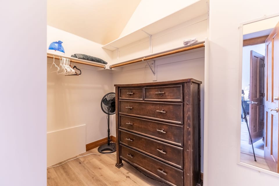 Your spacious walk-in closet offers ample storage with rich wooden drawers and hanging space for all your belongings.