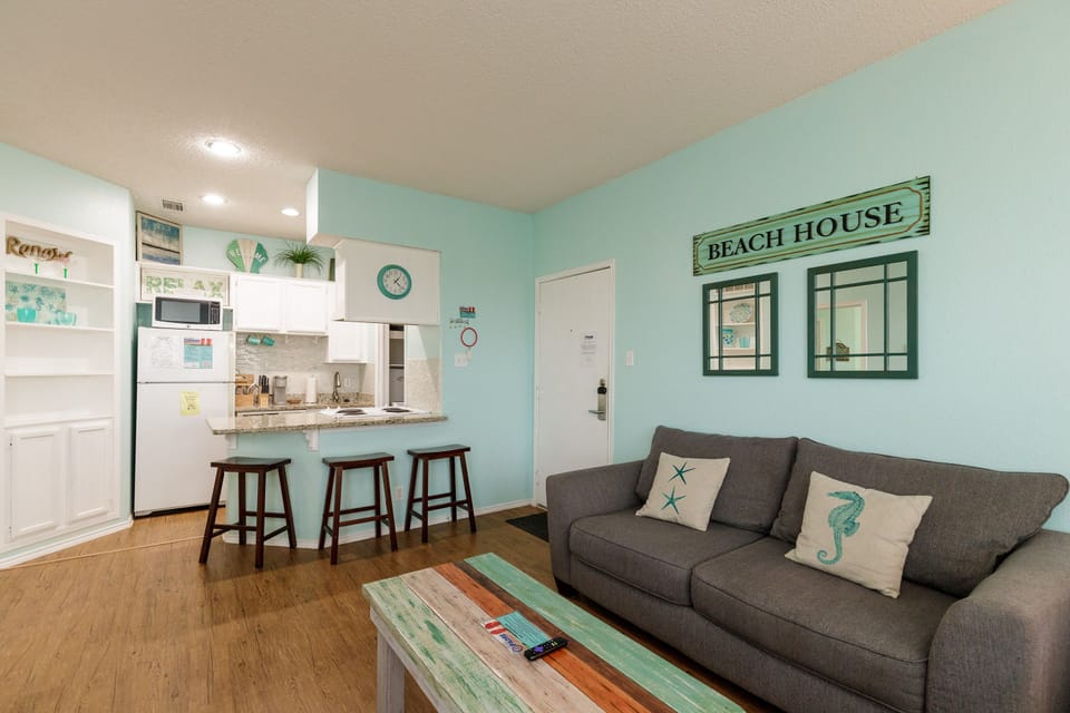Relax in your coastal-themed living space with comfy seating, beach-inspired decor, and an open kitchen perfect for preparing meals.
