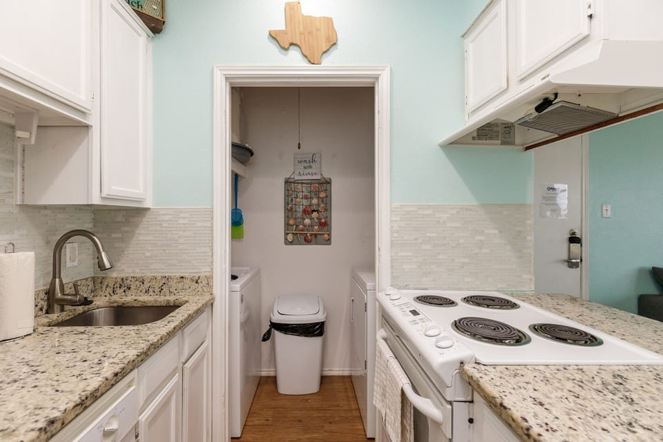 Your fully equipped galley kitchen features granite counters, white appliances, and charming Texas touches for easy meal prep.