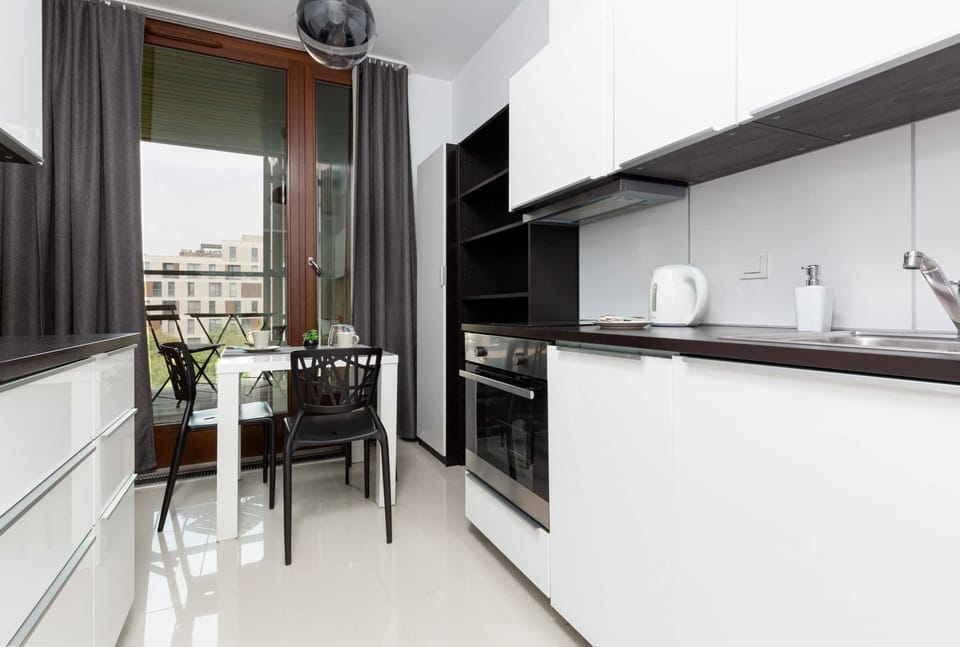 A modern kitchen with a white and black color scheme, featuring sleek cabinets and built-in appliances.
