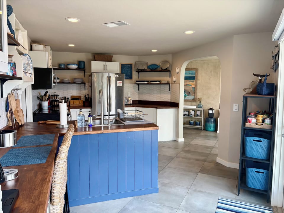 Well-stocked kitchen with sink at peninsula and breakfast bar seating for two.