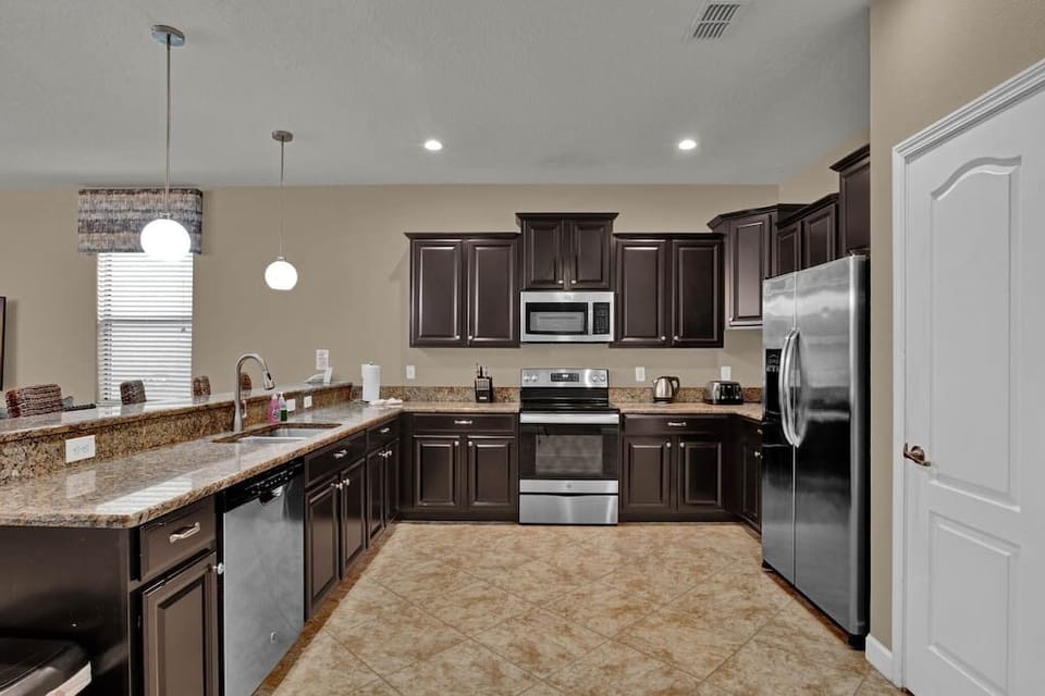 Kitchen with stainless steel appliances. New oven and microwave, pots and pans and coffee makers.