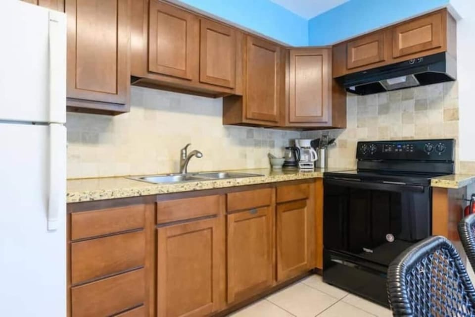 The kitchen is stocked with a full set of appliances including a refrigerator and basic kitchen utensils. 