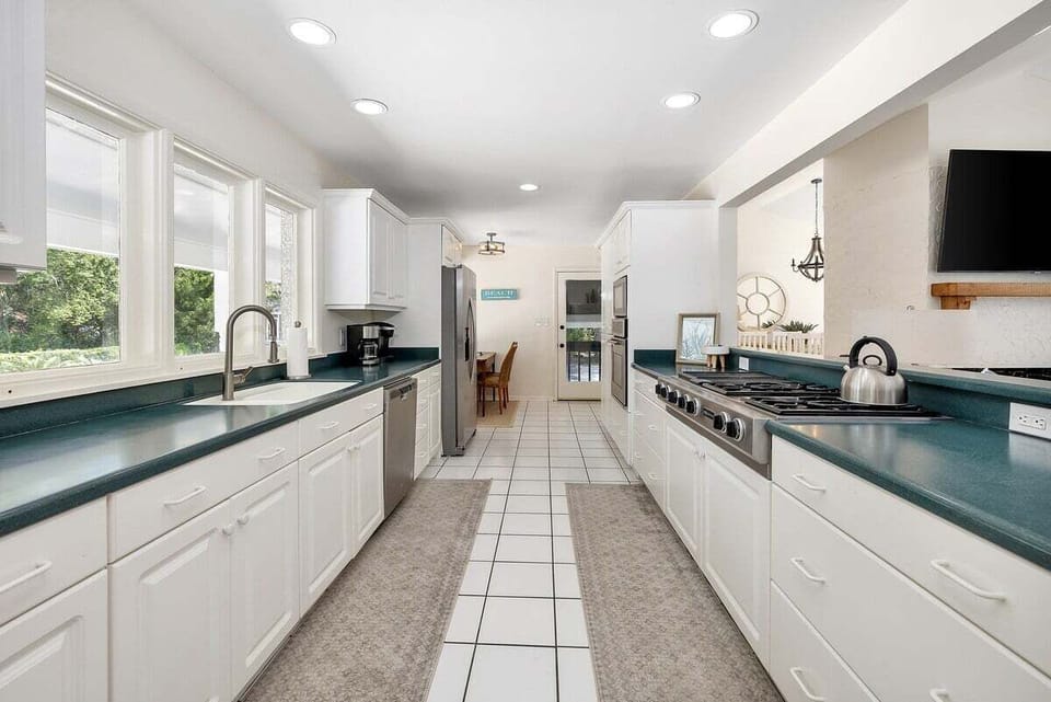 White galley kitchen with teal counters and stainless appliances