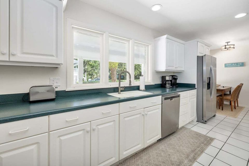 White kitchen with stainless steel appliances and teal countertops