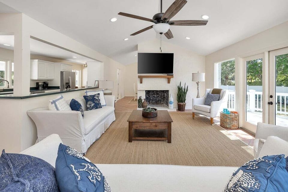 Bright living room with fireplace, TV, and ceiling fan
