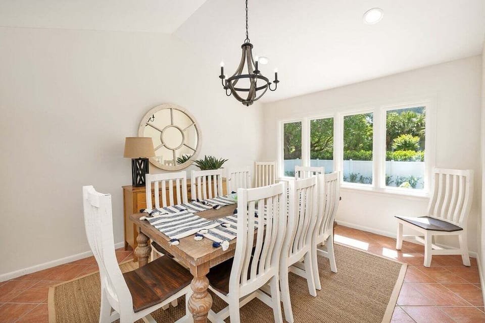 Bright dining room with white chairs and chandelier