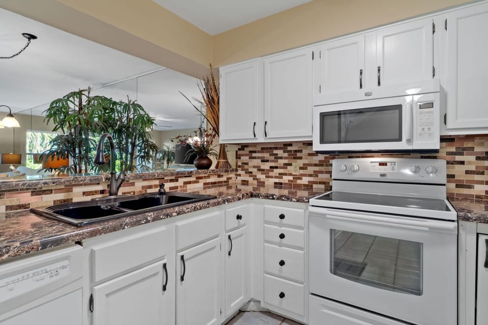 Kitchen features glass top stove/oven,  microwave, dishwasher, and fridge. 