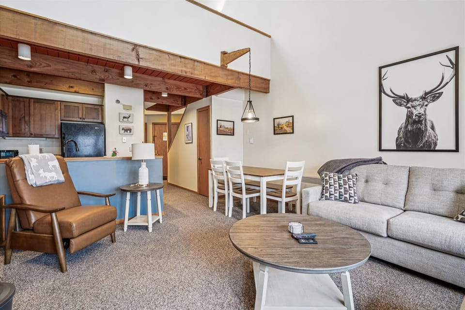 An open-concept design with rustic wood beams, dining space, and kitchen access, making it easy to cook, eat, and relax together in one connected space.
