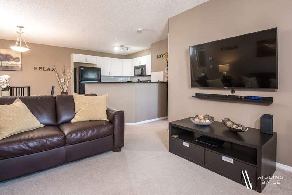 Living room with a Smart TV, cozy couches and walkout access to the balcony.