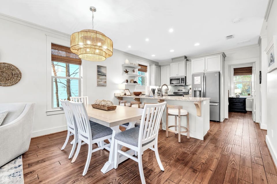 Your open-plan kitchen flows seamlessly into the dining area, where coastal charm meets modern comfort under warm pendant lighting.