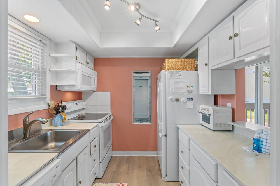Whip up your favorite meals in this bright, fully-equipped kitchen with modern appliances and cheerful coral accent walls.