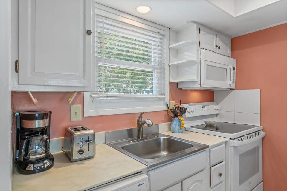 Your bright kitchen features modern appliances and warm coral walls, creating the perfect space for morning coffee and home-cooked meals.
