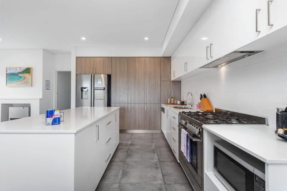Sleek modern kitchen featuring ample cabinetry, a full-size fridge, built-in oven, microwave, gas stove, and a spacious island—perfect for cooking, dining, and entertaining in style.