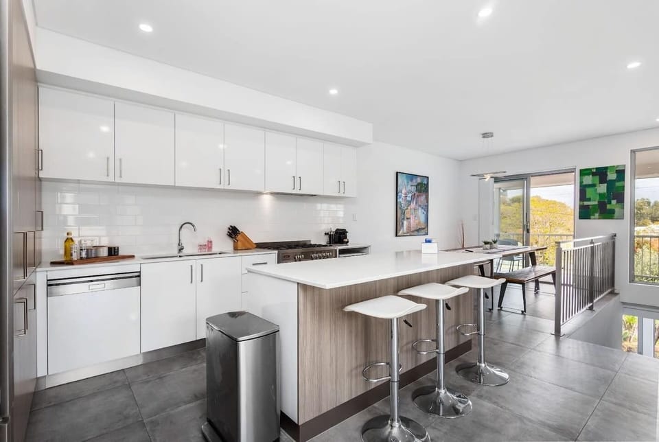 A modern kitchen featuring a spacious kitchen island, ample cabinets, a convenient sink, and essential tools like a knife set and other condiments—you'll find everything for easy meal preparation in this stylish space.