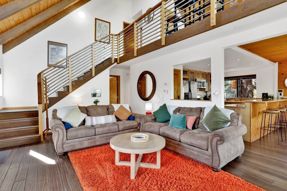Cozy mountain living room with a stone fireplace, comfy seating, and smart TV—perfect for relaxing evenings, movie nights, and warm cabin vibes after outdoor adventures.