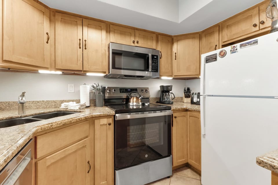 Your fully-equipped kitchen awaits with warm wood cabinets and granite countertops, complete with everything you need to whip up delicious meals during your stay.
