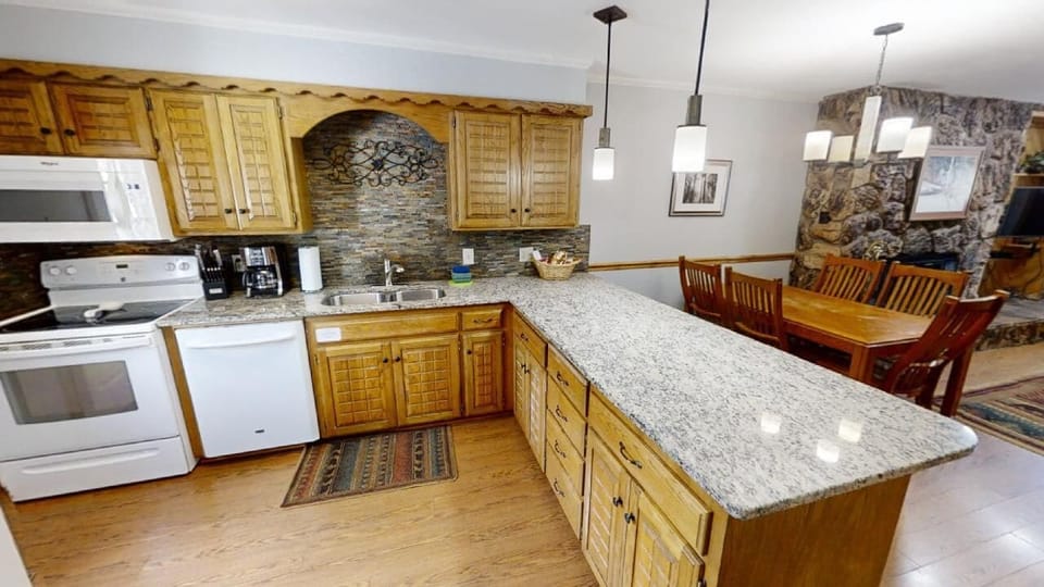Spacious kitchen with granite countertops and fully-equipped appliances flows into a welcoming dining area—perfect for preparing family meals and gathering together during your mountain retreat.