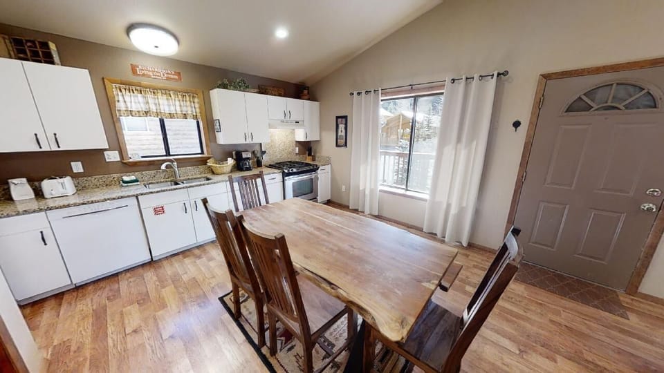 Step into your open-concept kitchen and dining space, where warm wood tones and bright natural light create the perfect setting for gathering around the rustic dining table after your adventures.