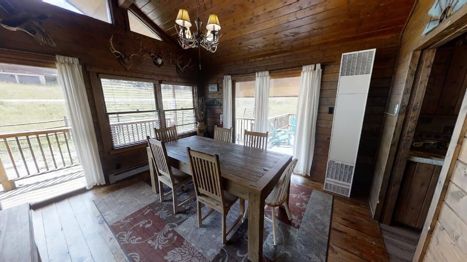 Gather around this rustic farmhouse table, where windows frame sweeping views and warm wood surrounds you. Perfect for sharing morning coffee or evening meals together.