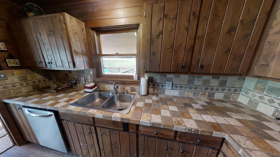 Your rustic cabin kitchen features handcrafted tile counters and natural wood accents, blending vintage charm with everyday convenience for your mountain escape.