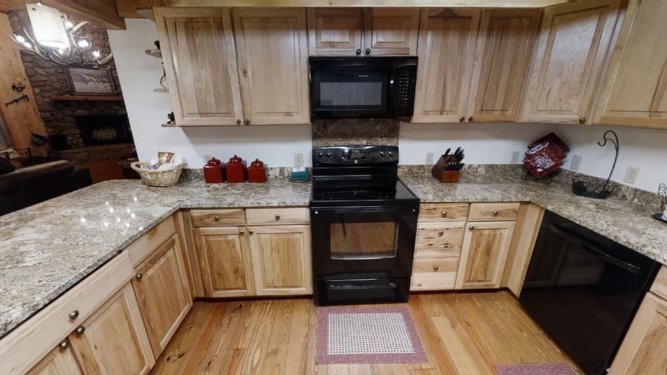 The fully equipped kitchen features granite countertops, modern black appliances, and plenty of storage space for preparing your favorite mountain meals together.