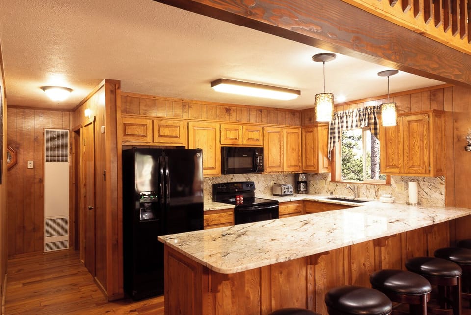 Your fully equipped kitchen invites you to gather and cook, with gleaming granite counters, a spacious island with seating, and warm wood cabinetry creating a cozy mountain retreat feel.
