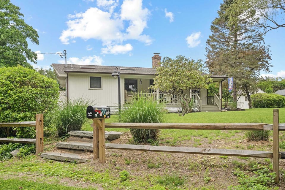 Front exterior from road with split-rail fence, brick chimney, and covered porch