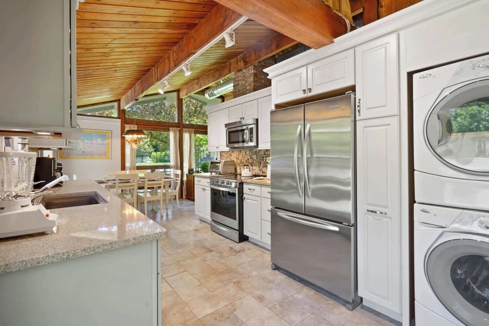 Kitchen with white cabinetry, stainless appliances, and stackable laundry