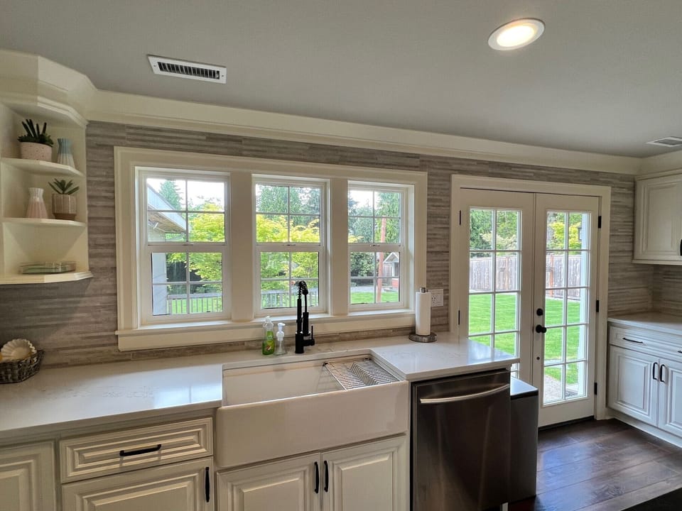 Kitchen sink and French doors look out to beautiful green backyard. 