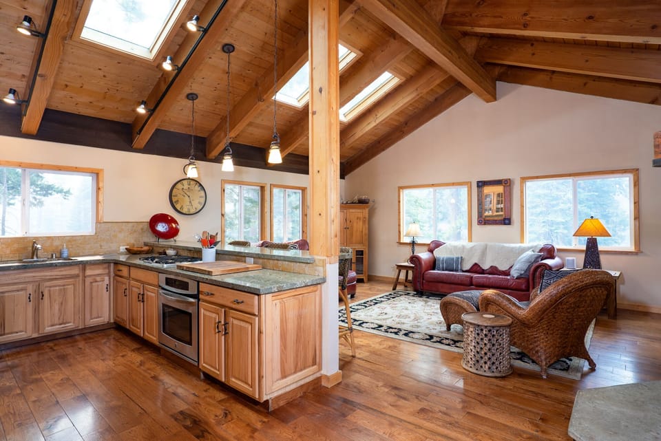 The open-concept living room flows into the kitchen, boasting high vaulted ceilings and stunning wood floors, offering a bright and spacious feel