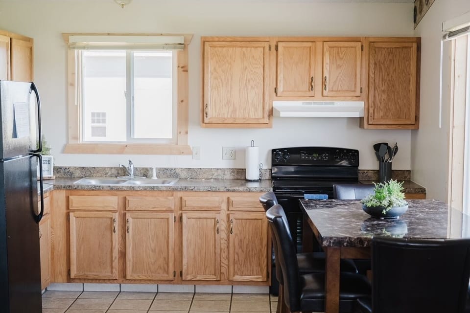 The kitchen is stocked with pots/dishes and towels. Table seats 6.