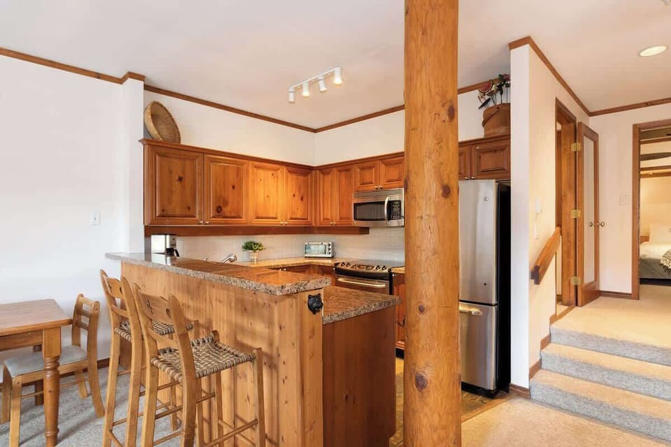 - Warm wooden kitchen with stainless steel appliances and bar stools  
- Granite counters and full amenities for home-style cooking  
- Perfect setup for après-ski meals and cozy nights in  
