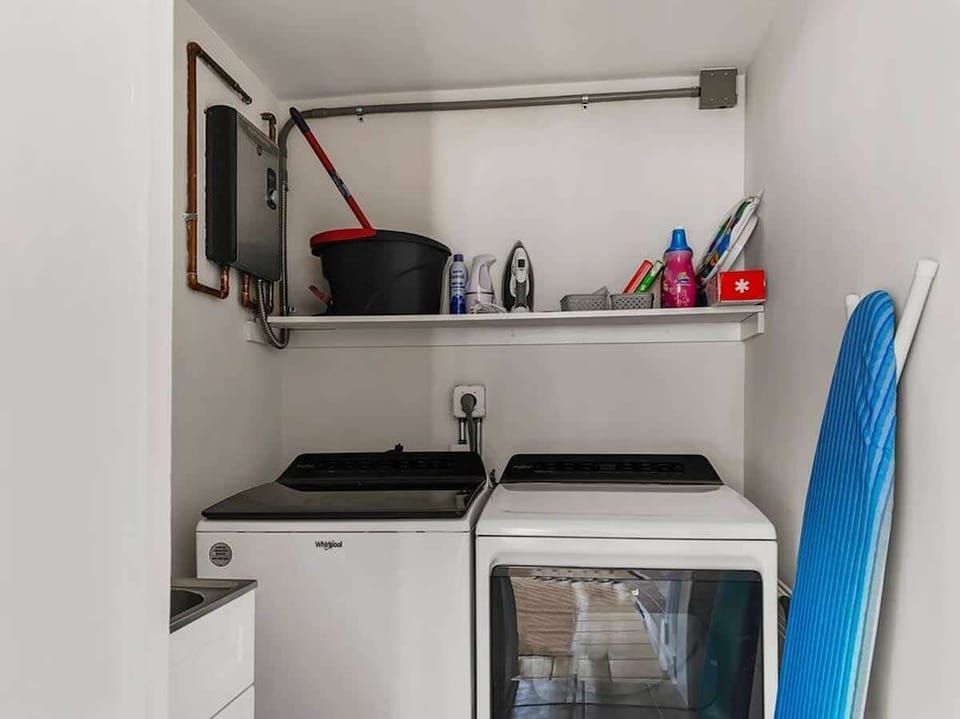A washing area with a washing machine, dryer, and some shelves.