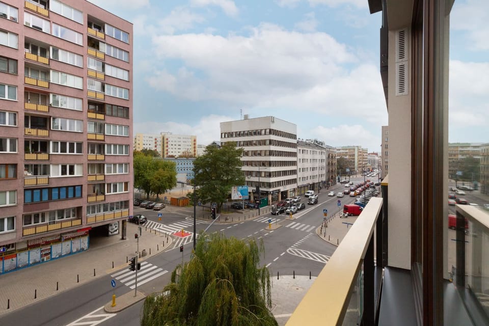 A city view from the balcony, showcasing a mix of modern architecture and greenery.
