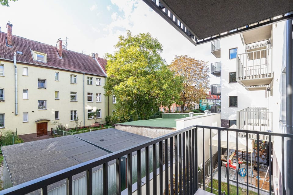 A balcony overlooking a peaceful residential area with green spaces.
