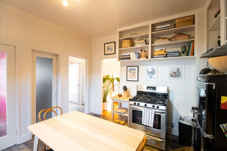Our charming kitchen features a microwave, hanging cabinets, generous storage, a fridge, and a cozy four-seat table, perfect for family dinners.