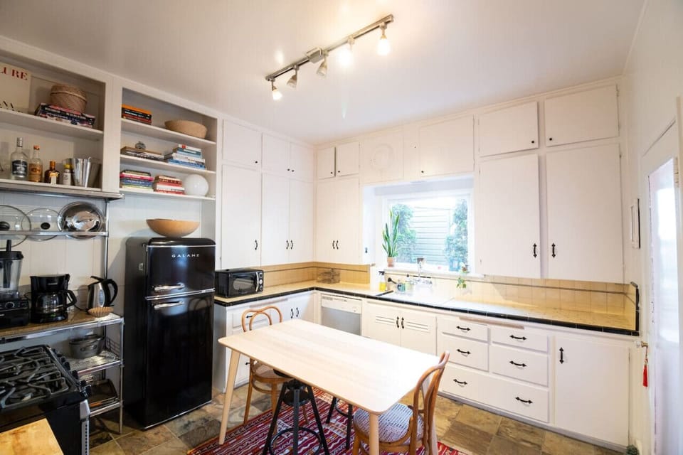 Cozy kitchen featuring a large countertop, sleek fridge, and a comfortable four-seat dining table—ideal for family gatherings.