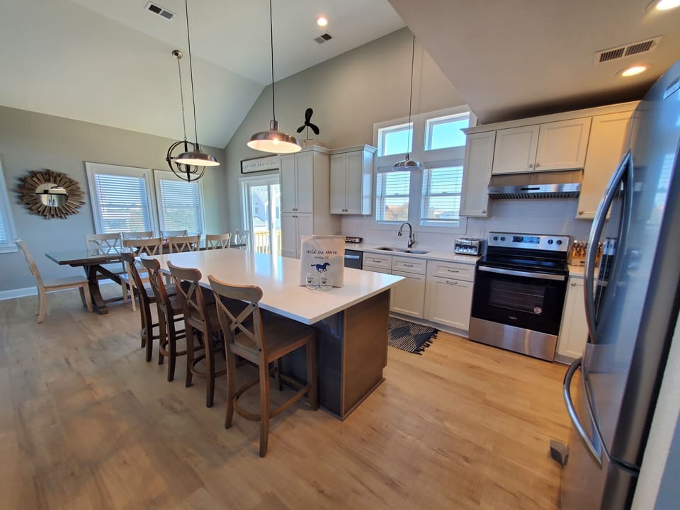Kitchen and Diningroom - Well-appointed kitchen featuring quartz, white and stainless appliances, and a sizeable island, ideal for preparing home-cooked meals.