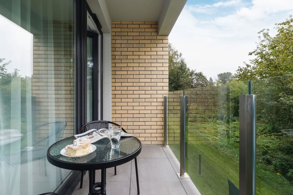 A balcony view with a small coffee table and green surroundings for outdoor relaxation.
