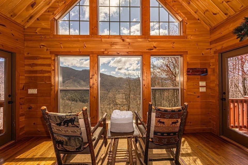 Sitting area positioned beside a wall of windows capturing Smoky Mountain scenery. The space highlights the cabin's elevated mountain location.