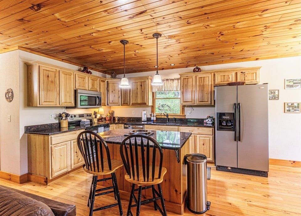 Open kitchen featuring breakfast bar seating, stainless steel appliances, and wood finishes throughout. Ideal for indoor dining and entertaining in the Smoky Mountains.