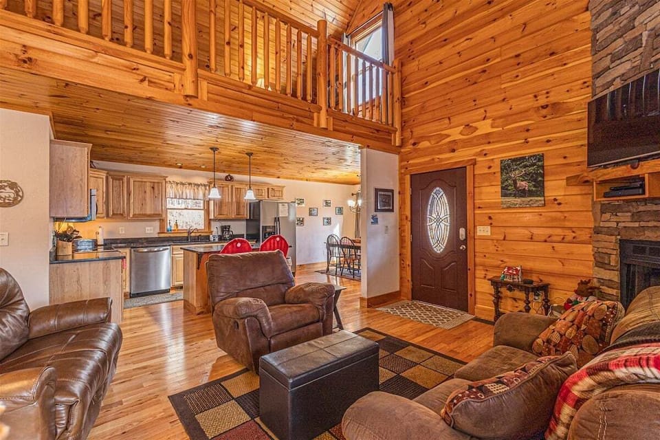 Open floor plan connecting the living room and kitchen with loft railing overhead. Spacious common areas provide gathering space for families and groups.