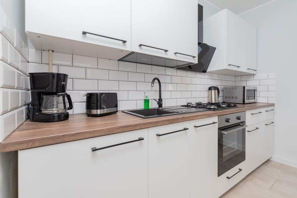A fully equipped kitchen with white cabinets, a large stove, and a window letting in daylight.
