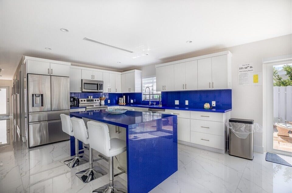 Crisp white cabinetry and striking blue accents bring island charm to every meal.