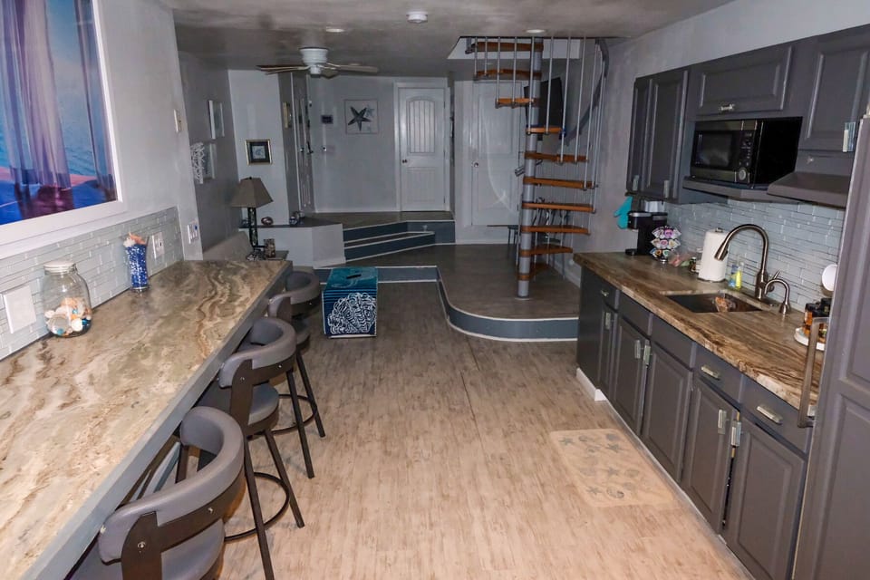 kitchen with counter seating. further is living room.