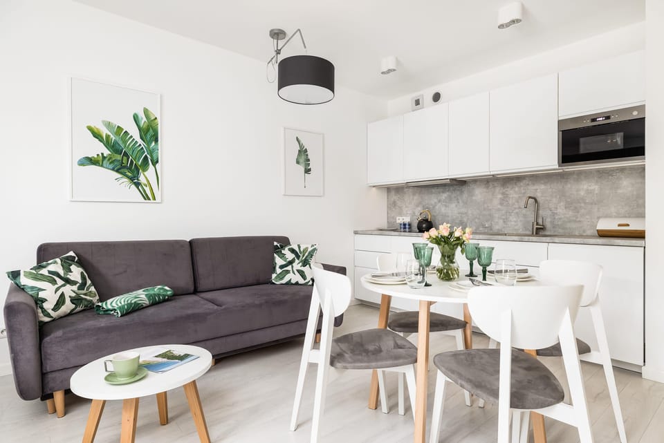 A sleek, open-plan kitchen adjacent to a dining table elegantly set with glassware and greenery.